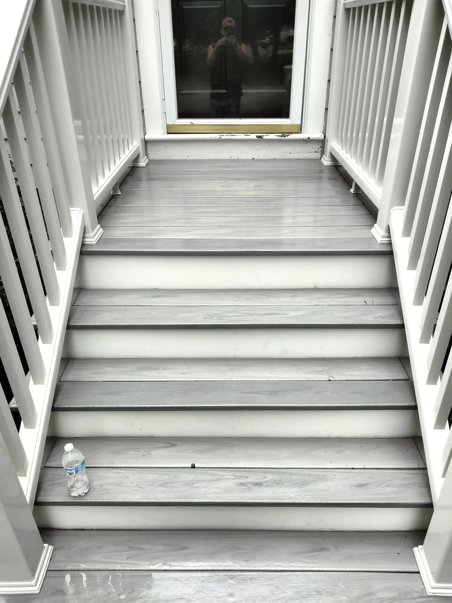 Clean composite deck stairs with white railings and trim, pressure-washed surfaces