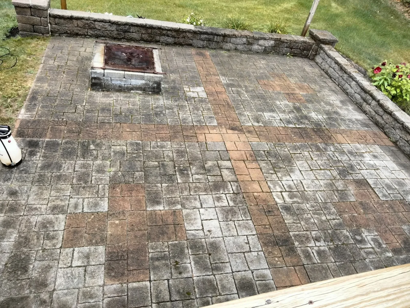 Cleaned patio with multi-colored concrete pavers, fire pit, and stone retaining wall