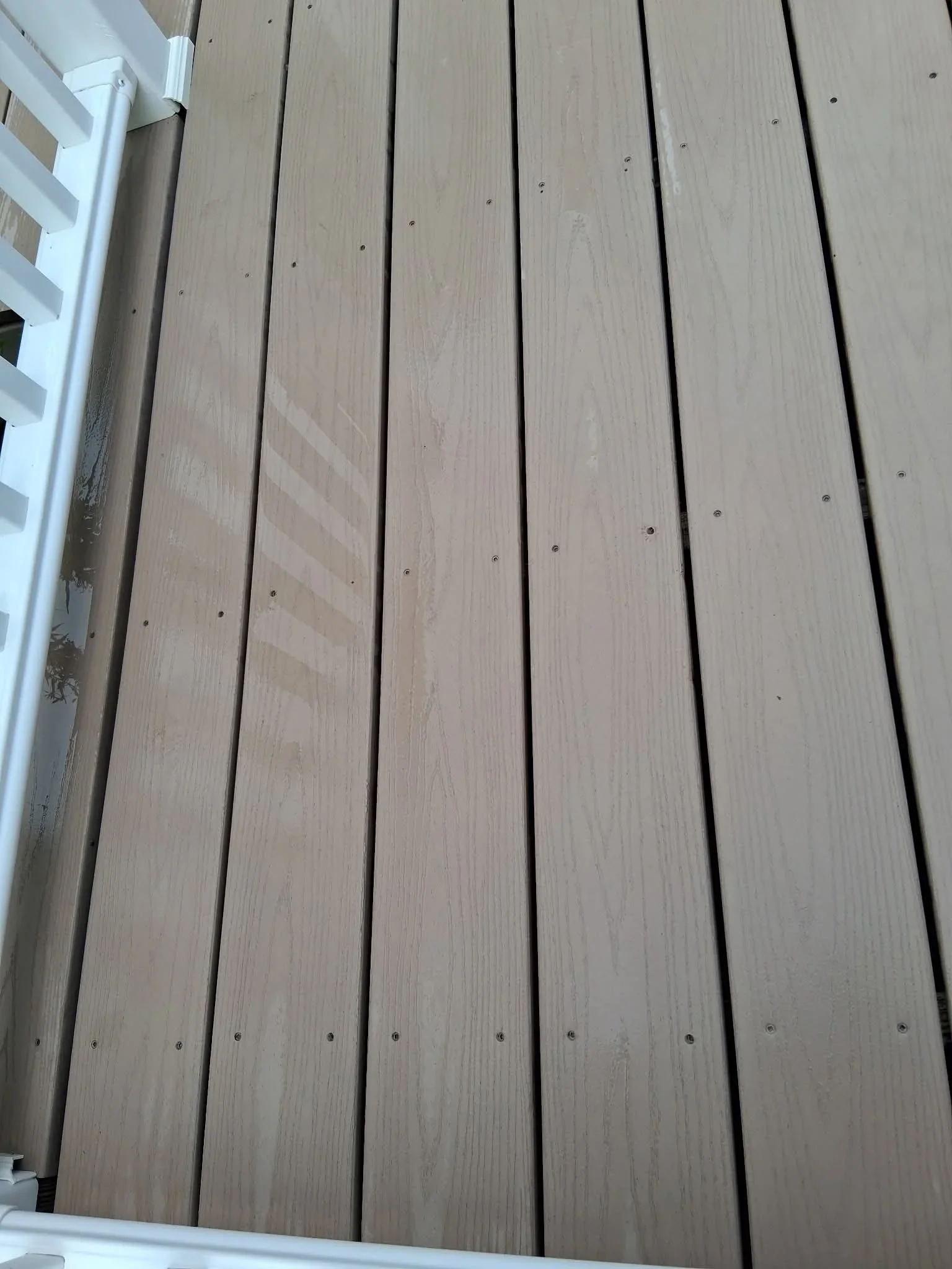 Clean composite deck boards with white trim, soft-washed surface showing restored color and texture