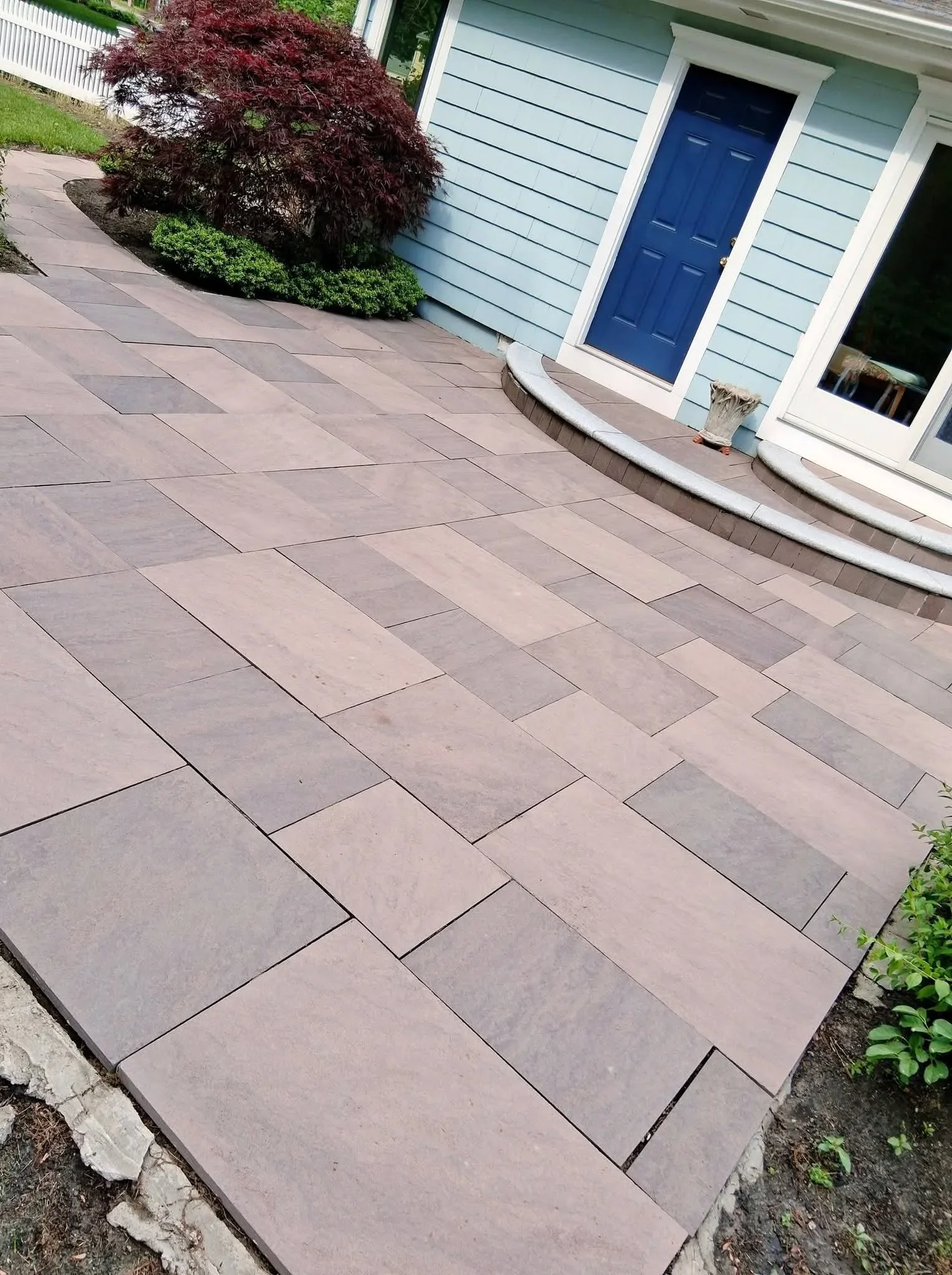 Clean herringbone paver patio with curved concrete edging and landscaping